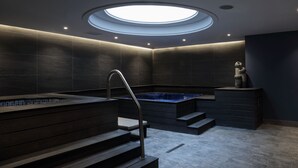 Un moderno spa con bañera de hidromasaje, escalones de madera y tragaluz.