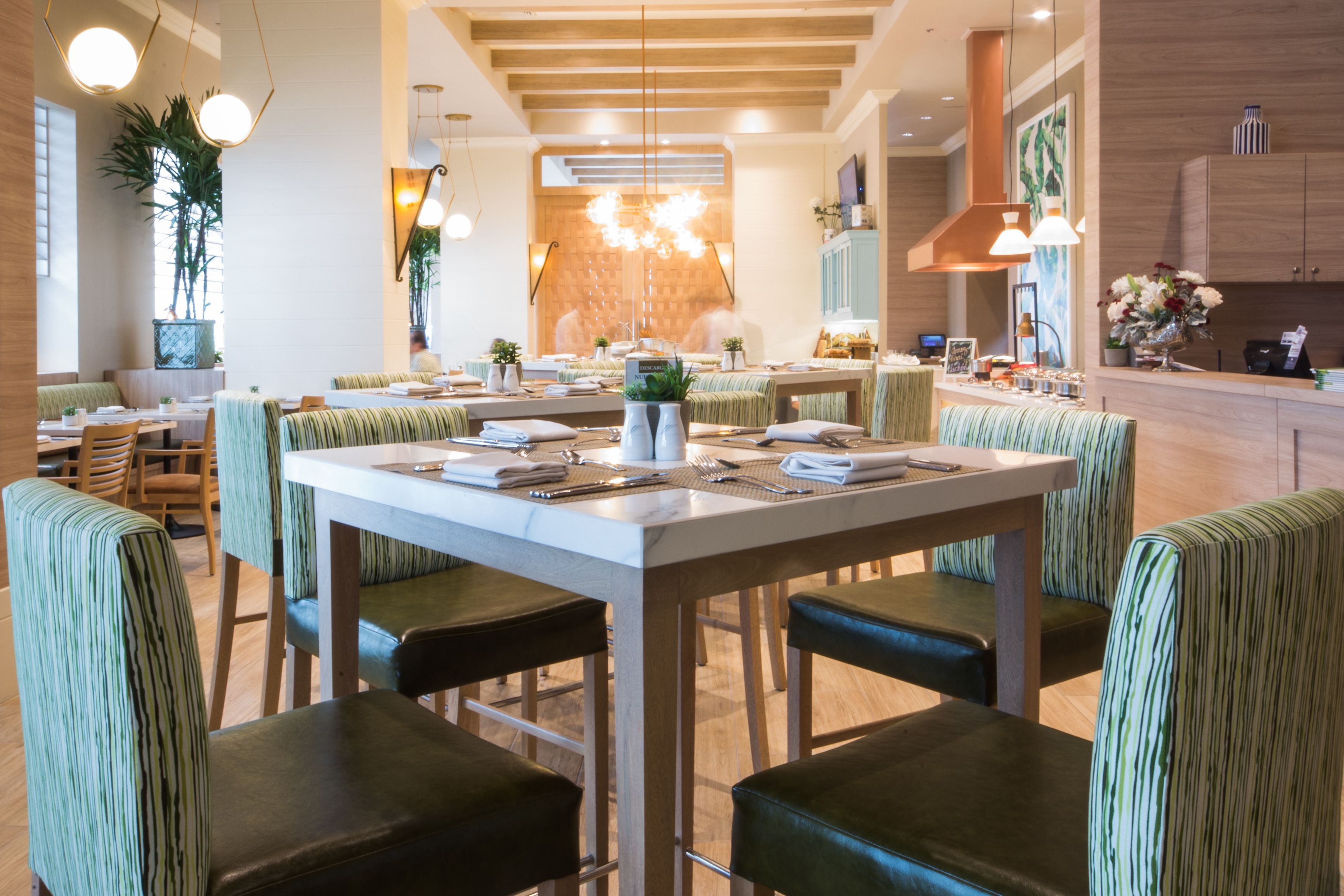 A restaurant with a long table, green-striped chairs, and a modern interior design.