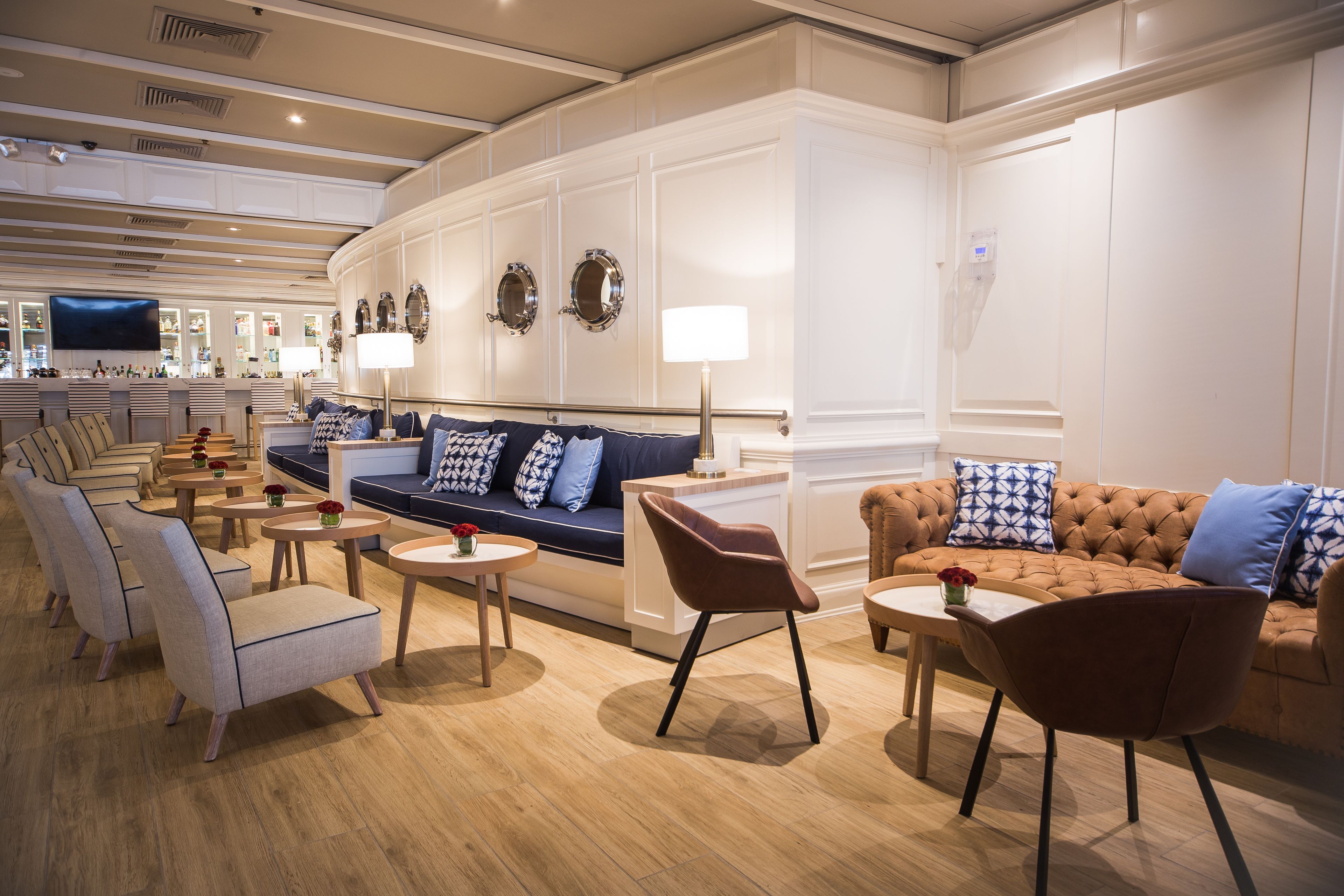 A modern hotel lobby with a sofa, armchairs, and a bar area.