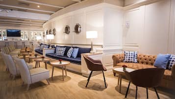 A modern hotel lobby with a sofa, armchairs, and a bar area.