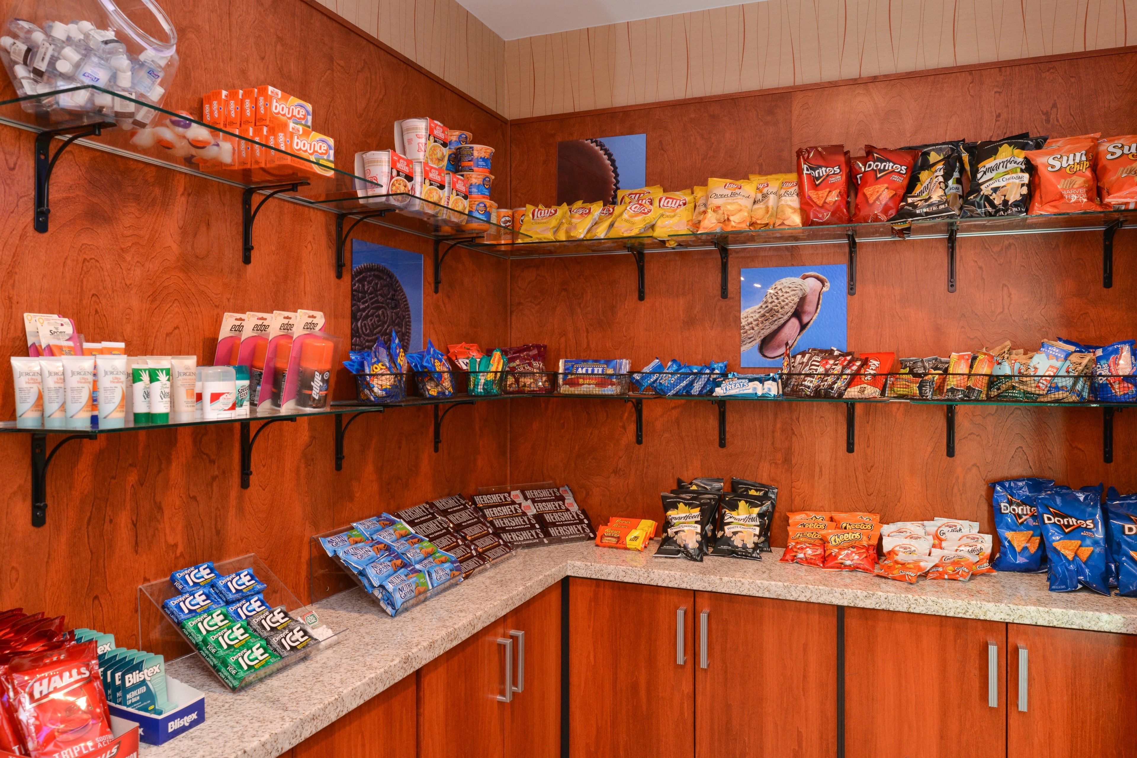 Een etalage met snacks en dranken in een winkel, met verschillende merken zoals Doritos, Lay's en Hershey's.
