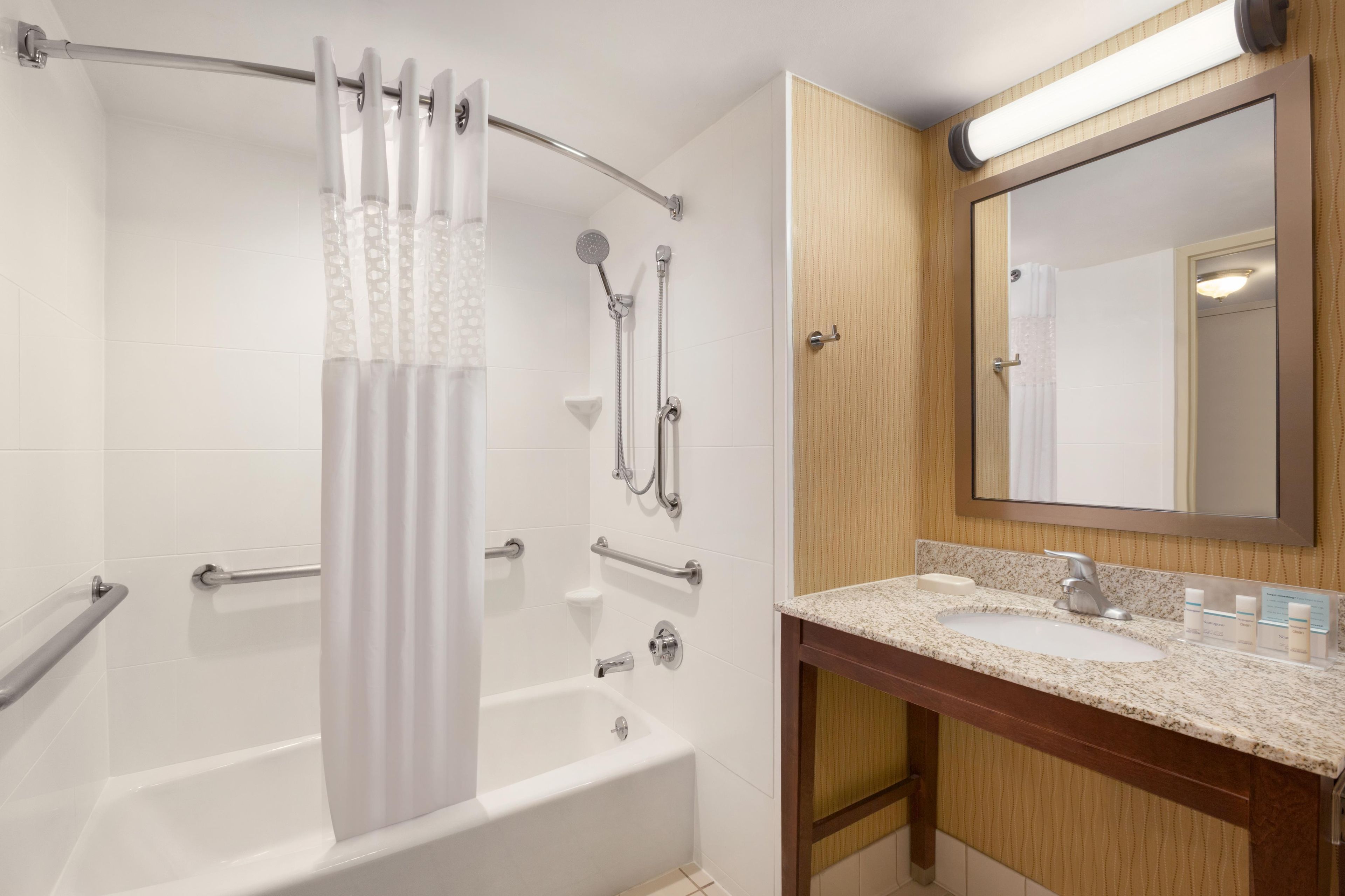 Un baño con bañera, ducha y tocador con lavabo y espejo.