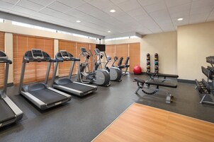 Un gimnasio con cintas de correr, elípticas y bancos de pesas.