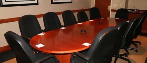 A conference room with a long table, black chairs, and framed artwork on the walls.