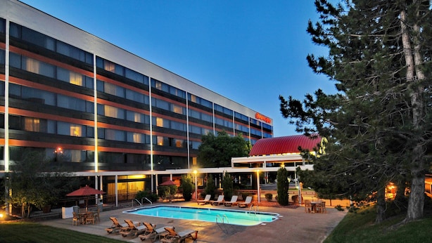 A hotel with a swimming pool, outdoor seating, and a covered area. - Hampton Inn Denver West Federal Center (Lakewood)