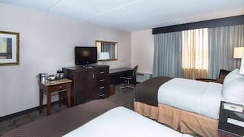 A hotel room with a bed, a desk, a television, and a window with curtains.