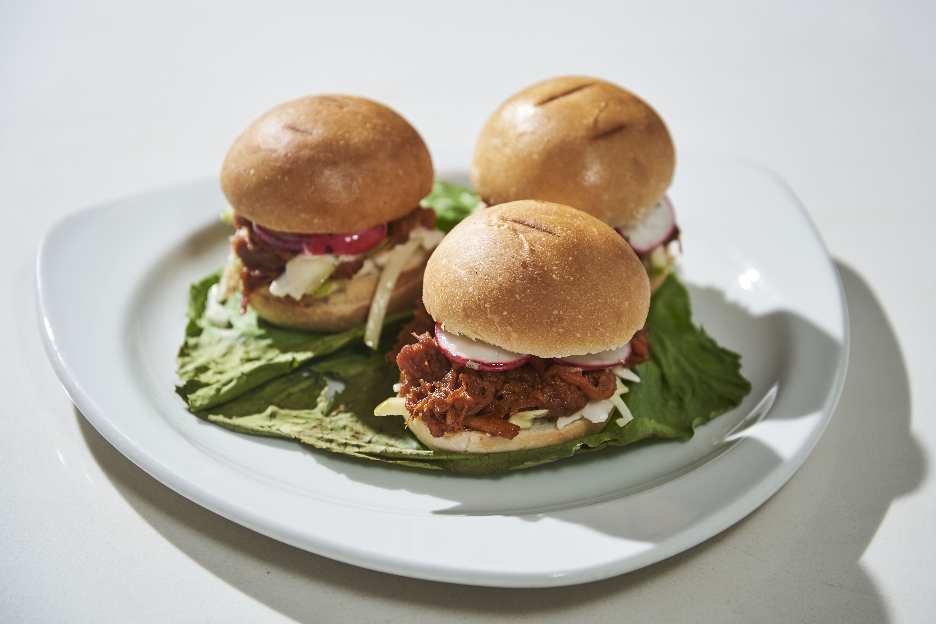 To sandwiches på en hvid tallerken med salat og rød løg.