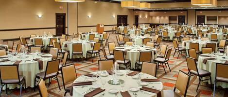 A large banquet hall with round tables set for dining, equipped with chairs and table settings.
