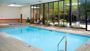 Una piscina interior con agua cristalina, suelo de baldosas y una escalera de acceso.