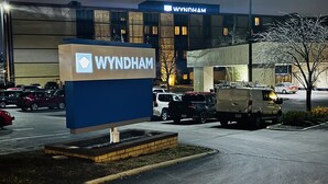 Señal de hotel Wyndham con un estacionamiento y vehículos en primer plano.