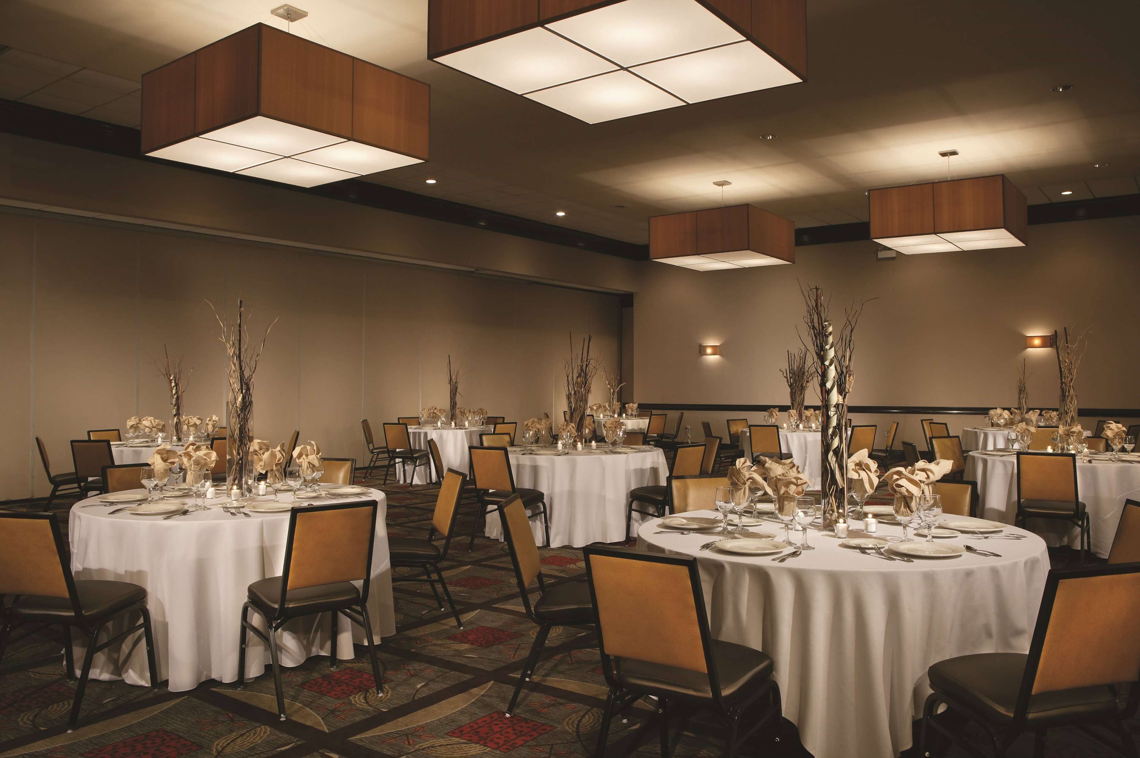A banquet hall with round tables set for dining, featuring white tablecloths and centerpieces.