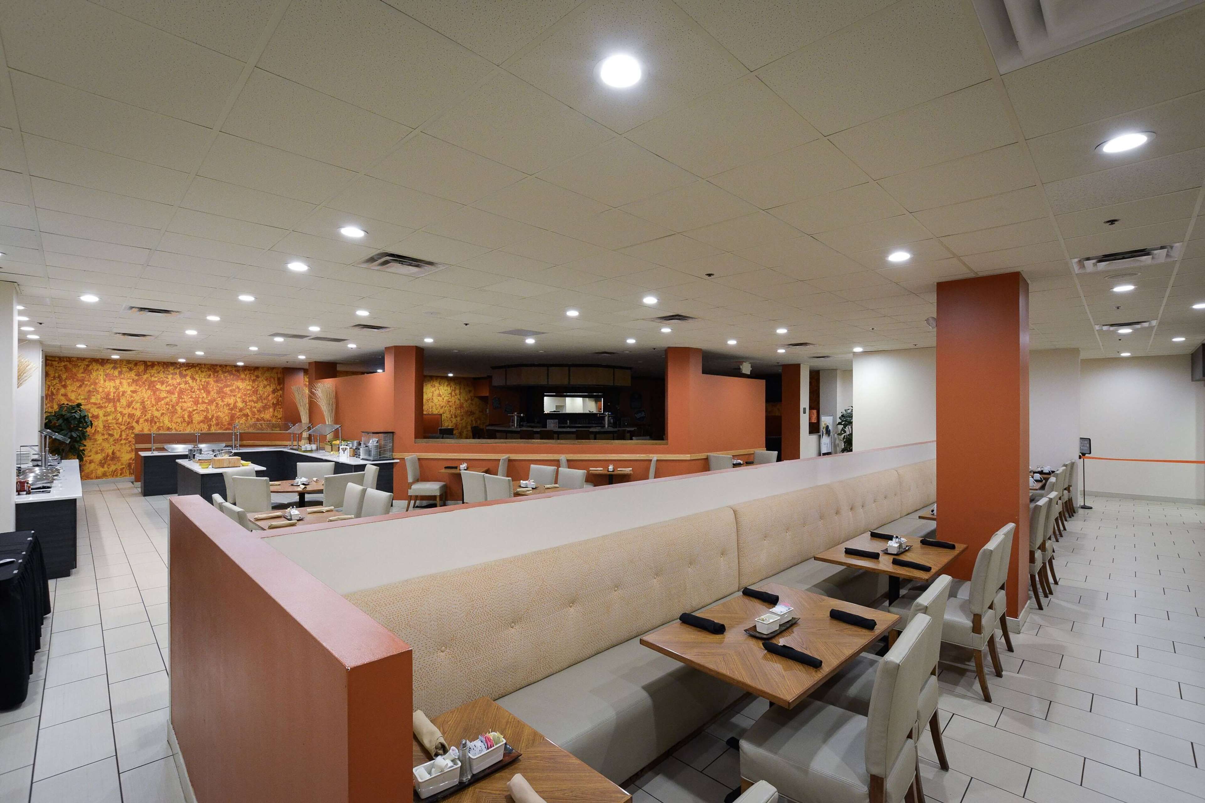 A modern restaurant with a long counter, booths, and a bar area.