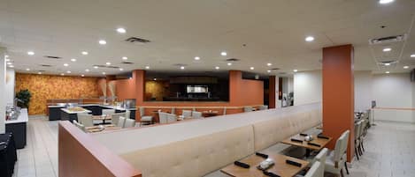A modern restaurant with a long counter, booths, and a bar area.
