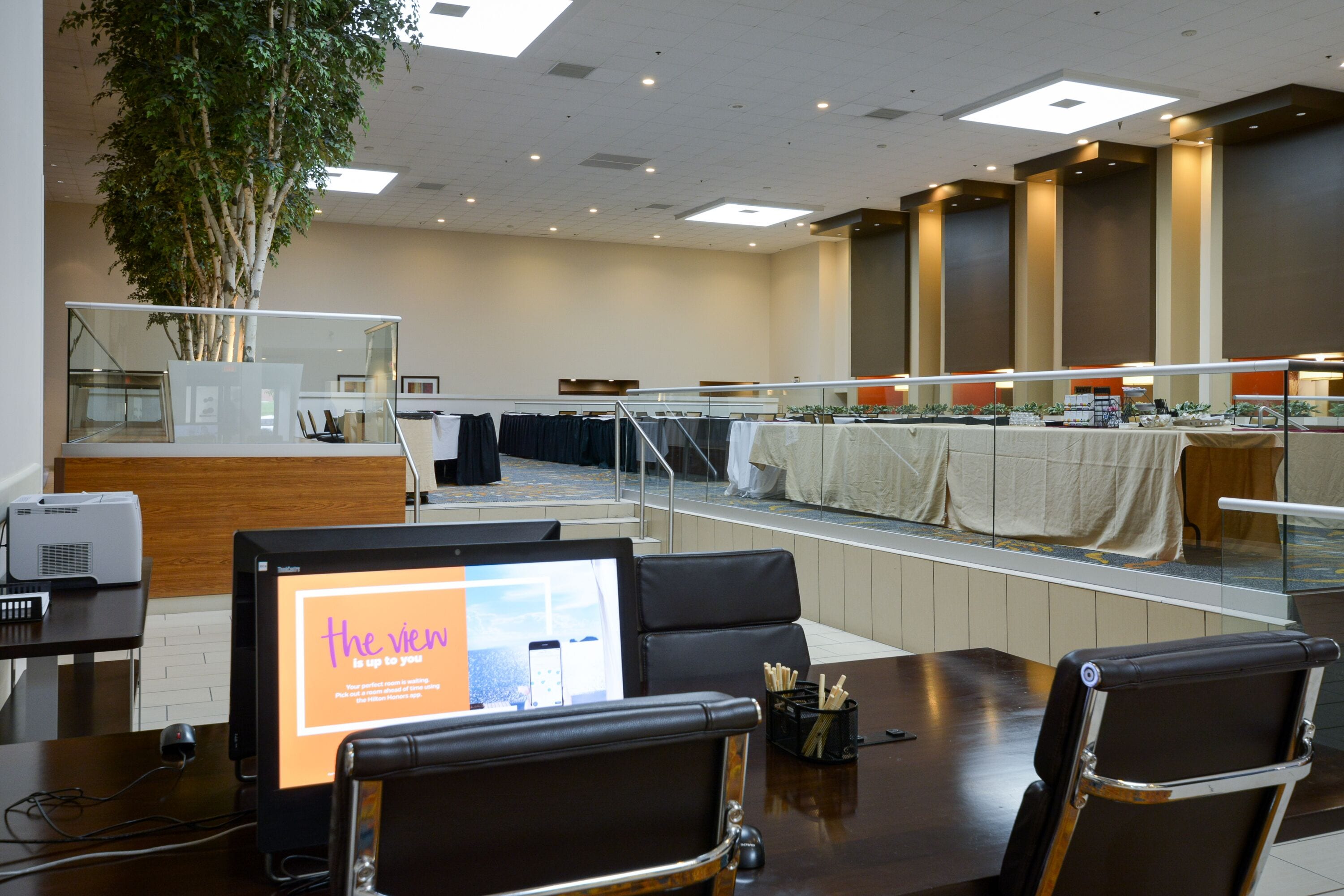 Une salle de conférence dotée d’un grand écran affichant du texte, un comptoir d’accueil et un espace détente avec des tables et des chaises.