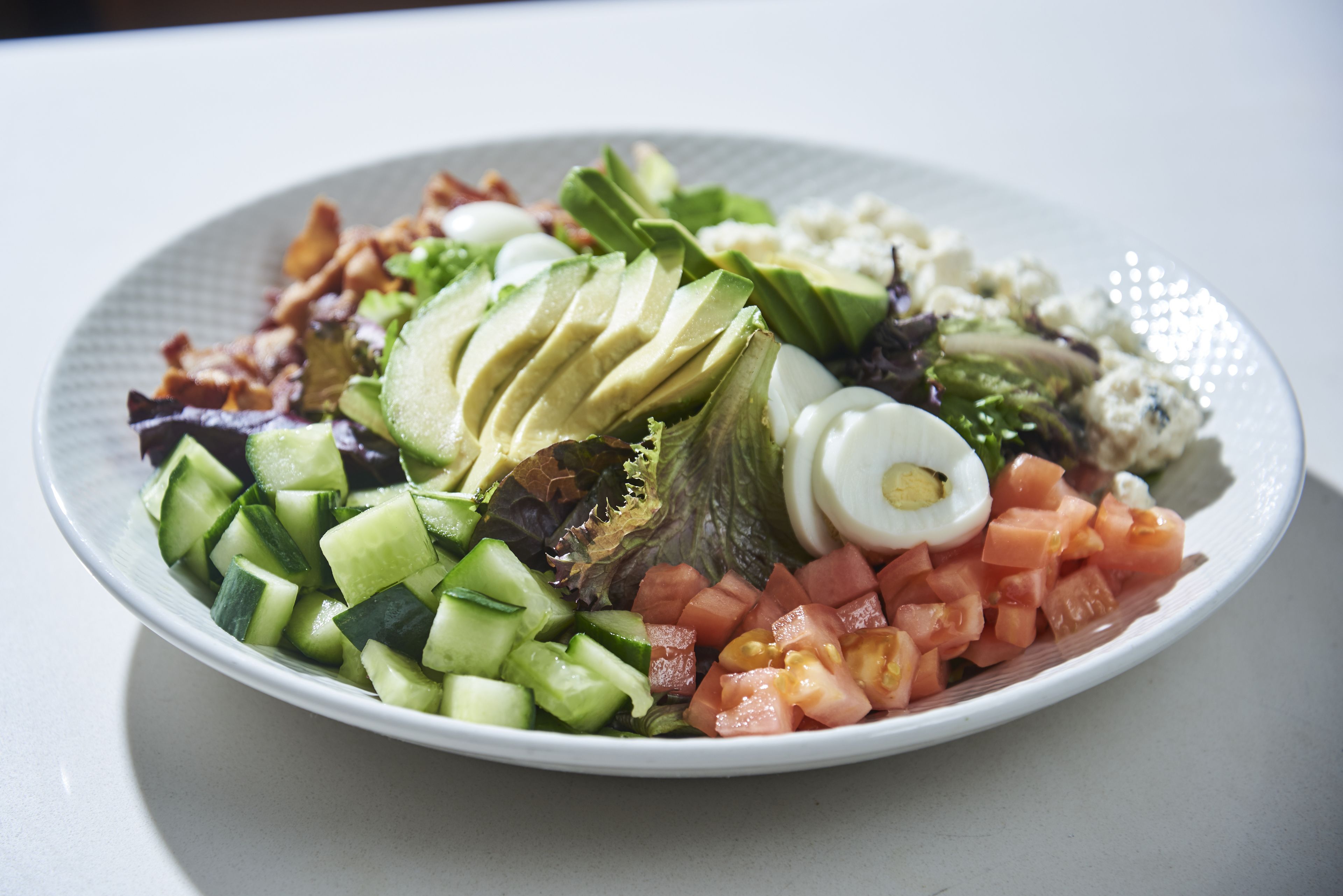 A plate of mixed salad with various vegetables and a boiled egg.