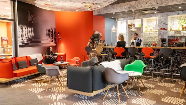 A modern lounge area with seating, a bar, and a patterned ceiling.