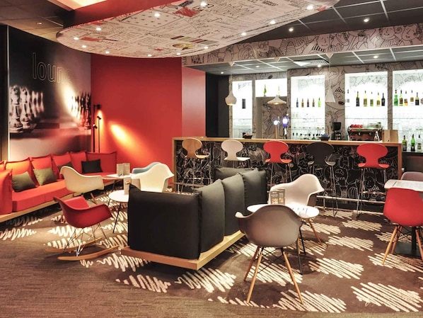 A bar area with a red and black color scheme, modern furniture, and a patterned carpet.