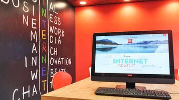 Una computadora con una pantalla que muestra 'Free INTERNET GRATUITO' en varios idiomas, una pizarra con palabras coloridas y una pared roja.