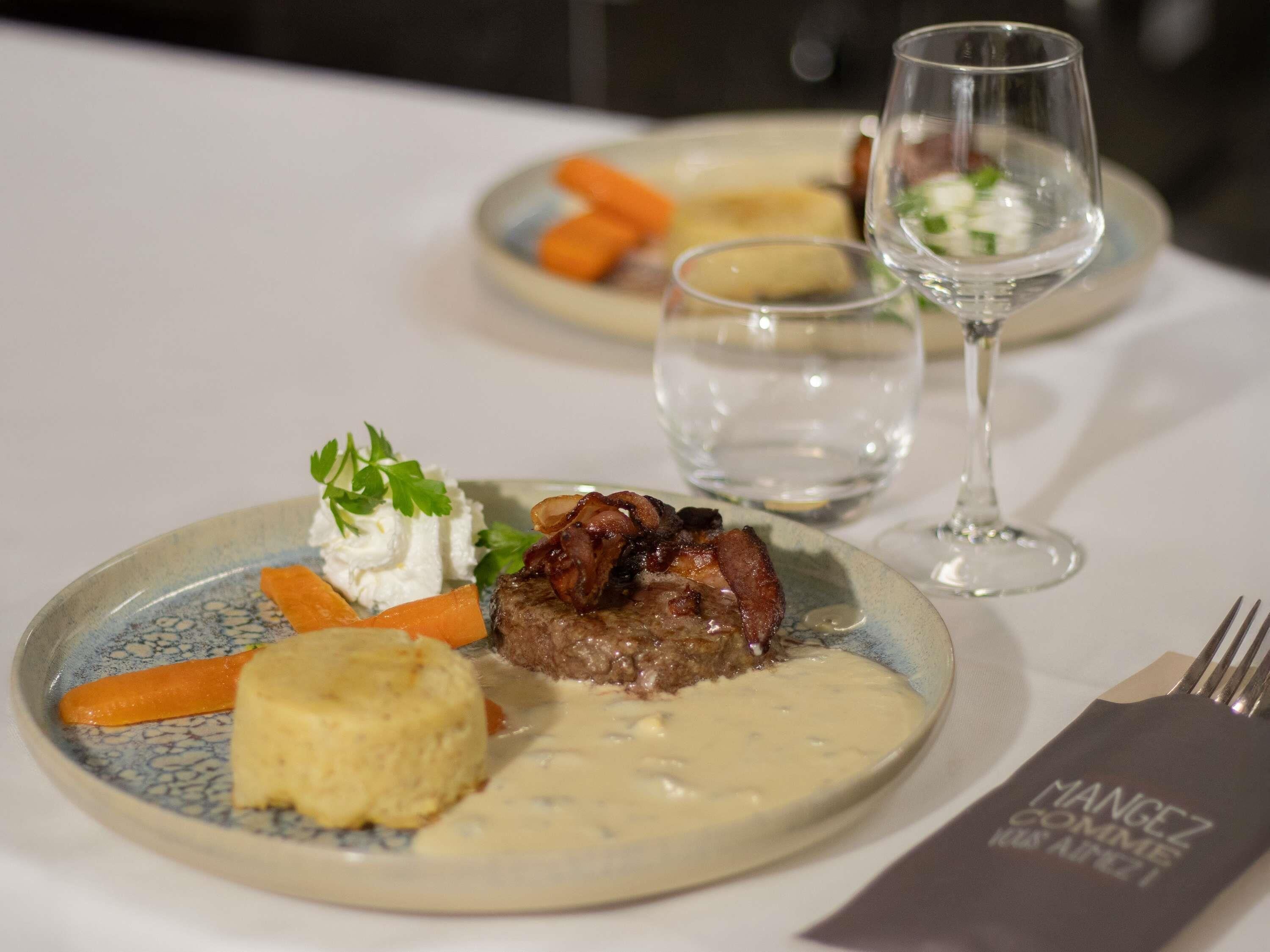 A dining table with plates of food, a glass of water, and a menu.