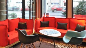 A modern interior with a red sofa, black and blue chairs, and a small table with a magazine.
