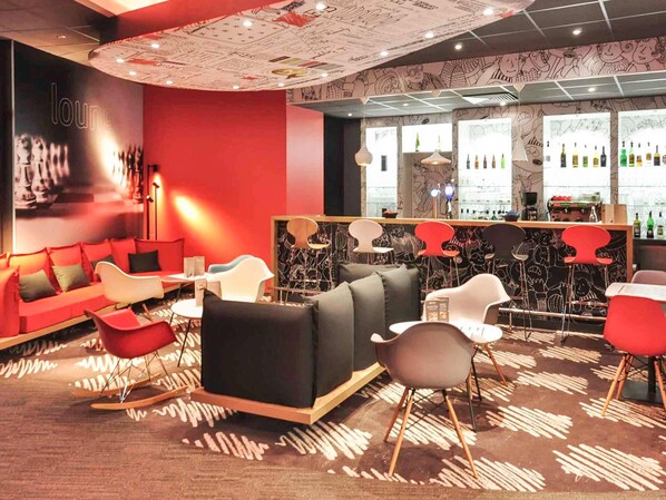 Zona de bar con una decoración en rojo y negro, muebles modernos y un papel tapiz con diseño.
