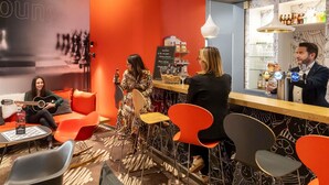 A modern lounge area with red and black decor, a bar, and seating arrangements.