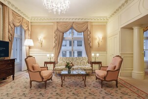 Uma sala de estar formal com sofá, duas poltronas, uma mesa de centro e televisão.