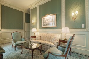 Uma sala de estar formal com um sofá, duas poltronas, uma mesa de centro e luminárias fixadas na parede.