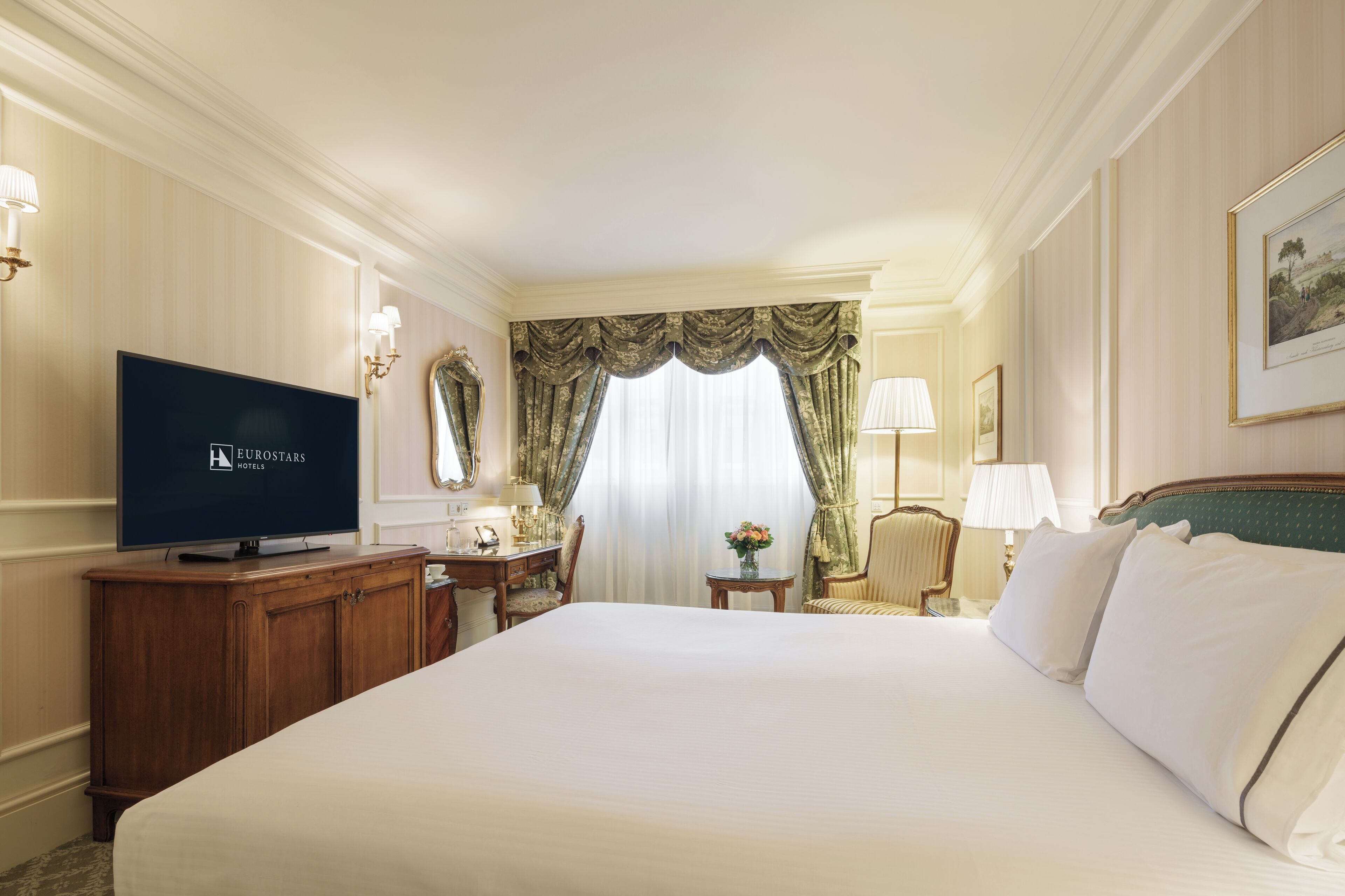 Une chambre d’hôtel avec un grand lit, une télévision, un bureau avec une chaise et une fenêtre avec des rideaux.