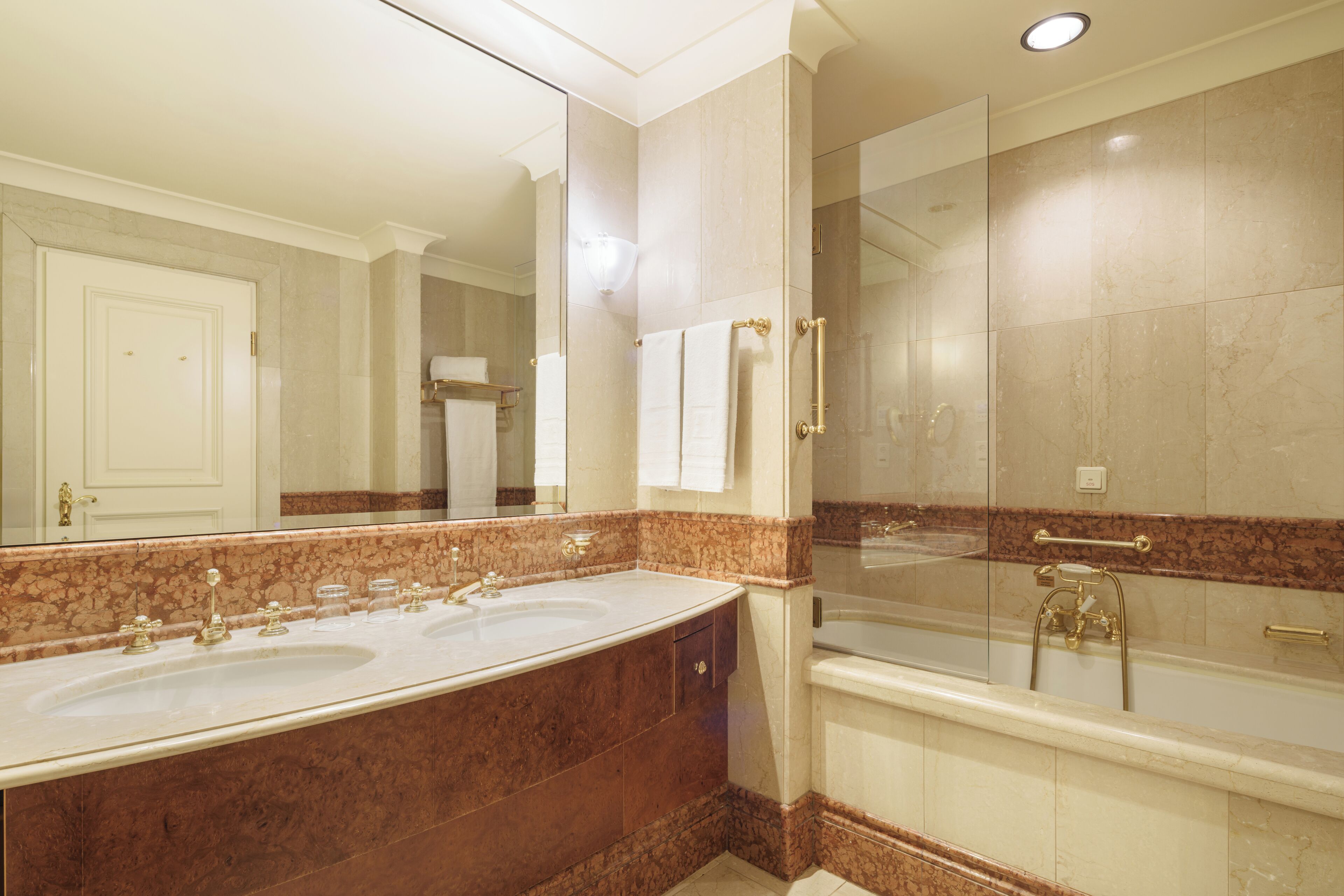 A modern bathroom with a large marble sink, a bathtub, and a glass-enclosed shower.