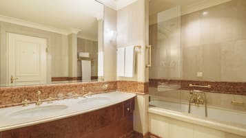 A modern bathroom with a large marble sink, a bathtub, and a glass-enclosed shower.