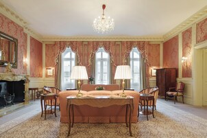 Um quarto luxuoso com uma cama grande, duas mesas de cabeceira, um candelabro e uma lareira.