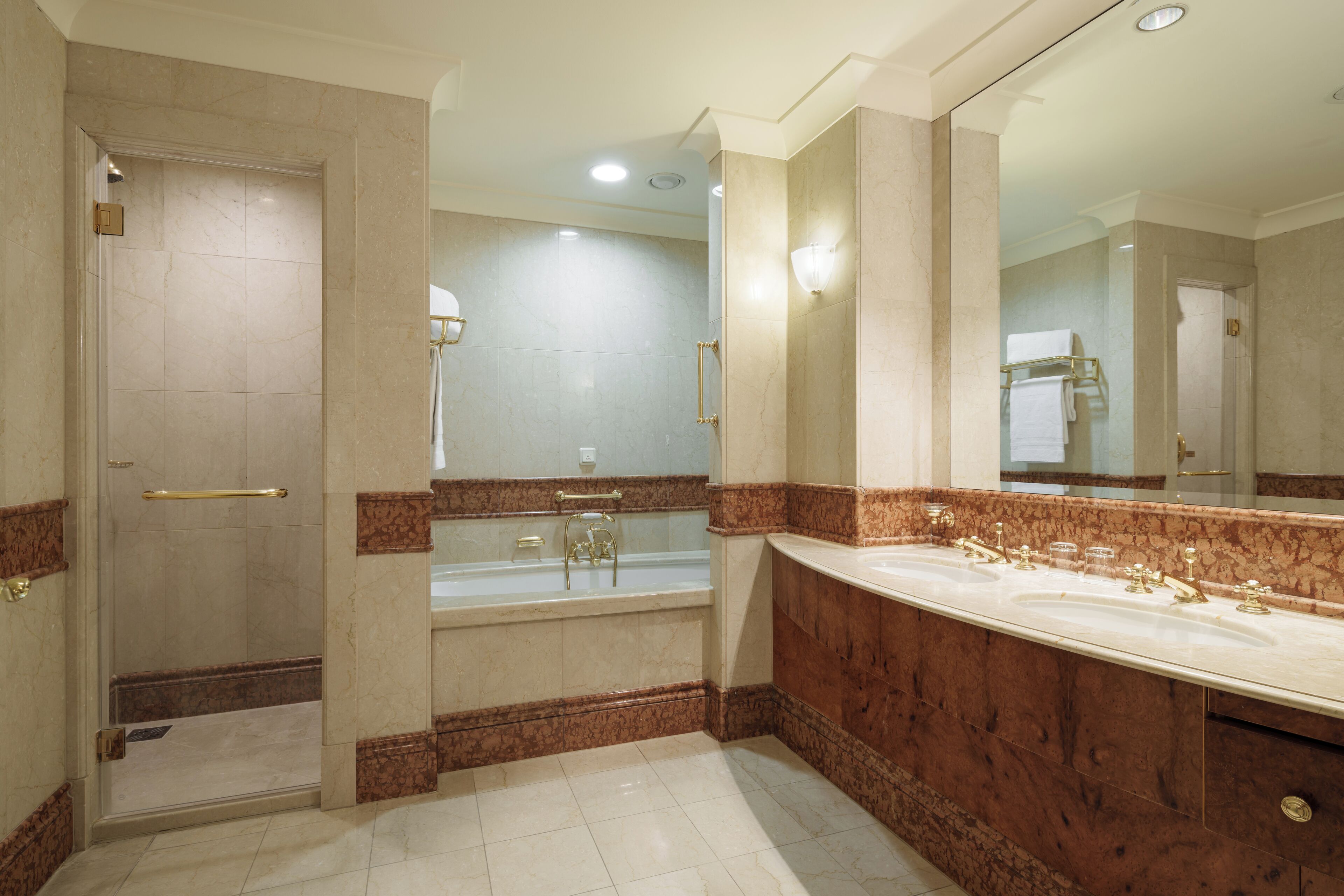 A bathroom with a large mirror, a bathtub, and a shower area.