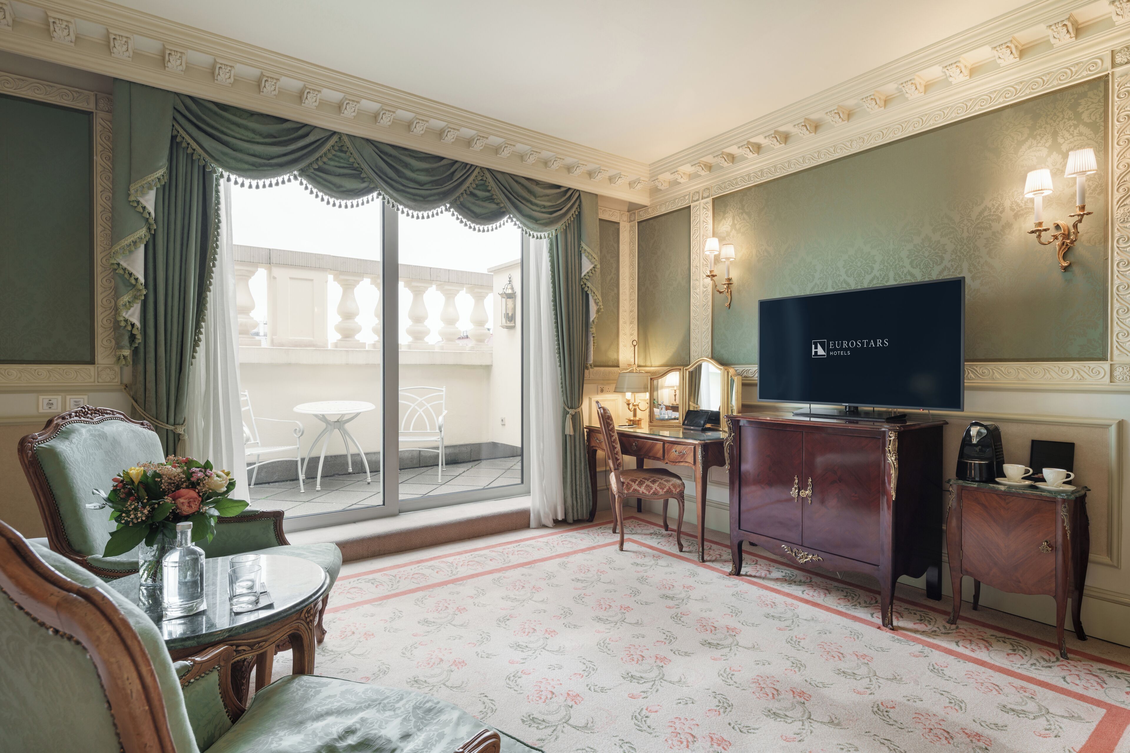 A hotel room with a large window, a television, a desk, and a chair.