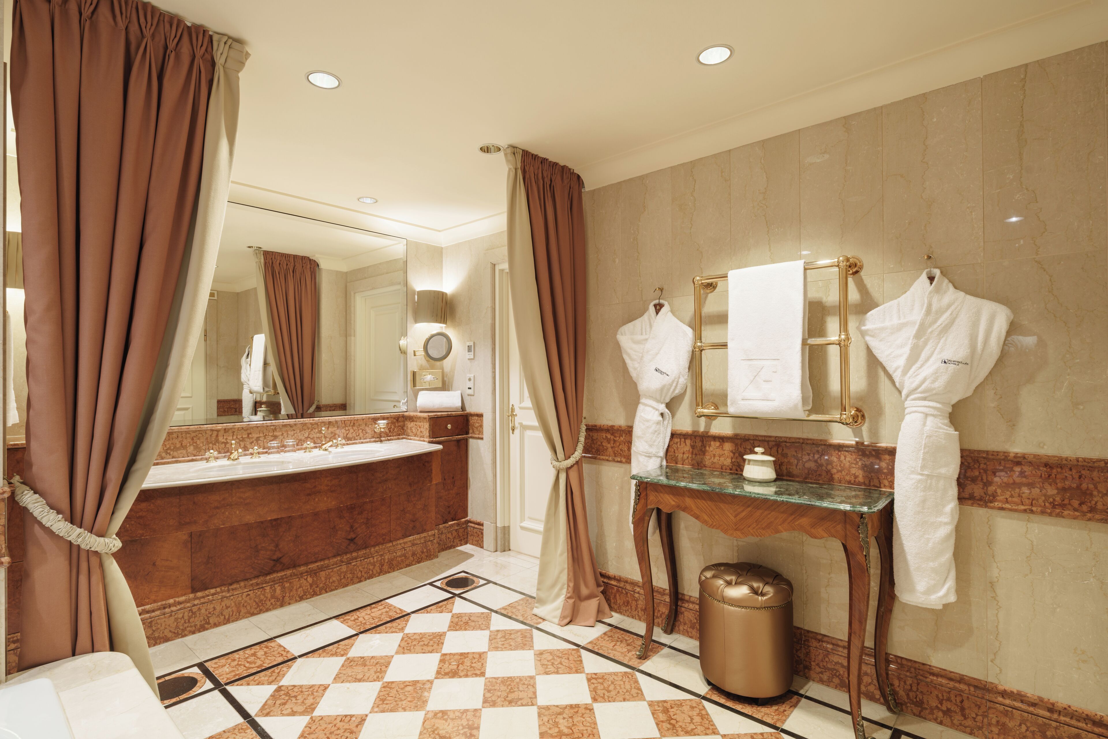 Un bagno con un vanità in marmo, un ampio specchio e un portasciugamani.