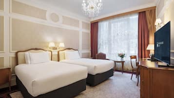 Ein Hotelzimmer mit zwei Betten, einem Fernseher, einem Schreibtisch und einer Kandelaber.