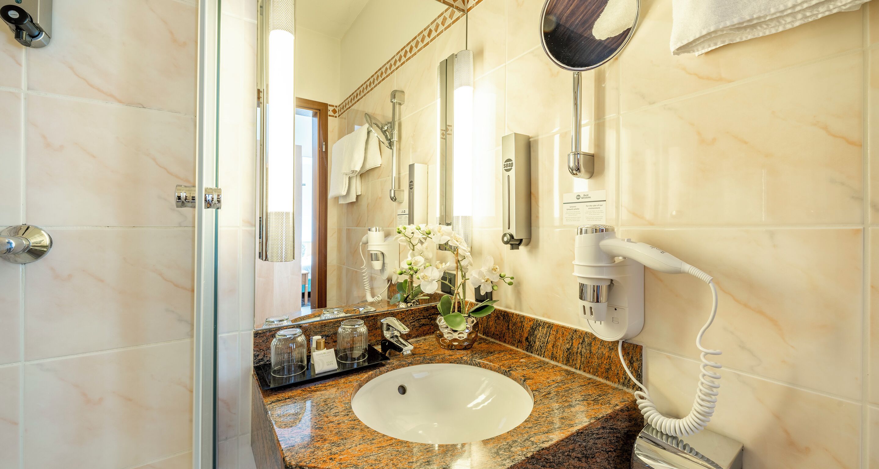 A bathroom with a sink, mirror, hairdryer, and a towel rack.