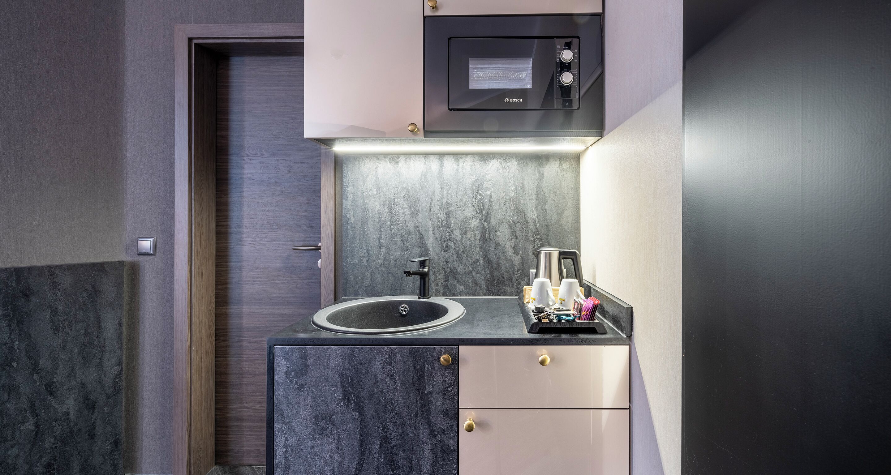 A compact kitchen with a Bosch microwave, a sink, and a coffee maker.