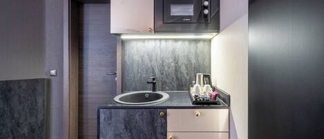 A compact kitchen with a Bosch microwave, a sink, and a coffee maker.