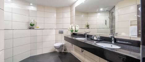 Un baño moderno con dos lavamanos, un inodoro y una ducha.