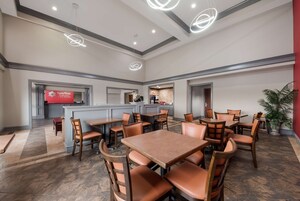 Un vestíbulo de hotel con varias zonas de estar, una recepción y un área de bar.