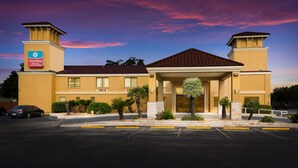A hotel with a central entrance, a parking lot, and a clear sky. - SureStay Plus Hotel by Best Western San Antonio North (San Antonio)