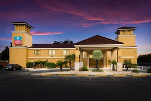 Un hotel con entrada principal, aparcamiento y cielo despejado.