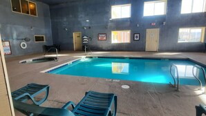 An indoor swimming pool with clear water, surrounded by blue lounge chairs and a tiled floor. - Quality Inn & Suites Grants - I-40 (Grants)