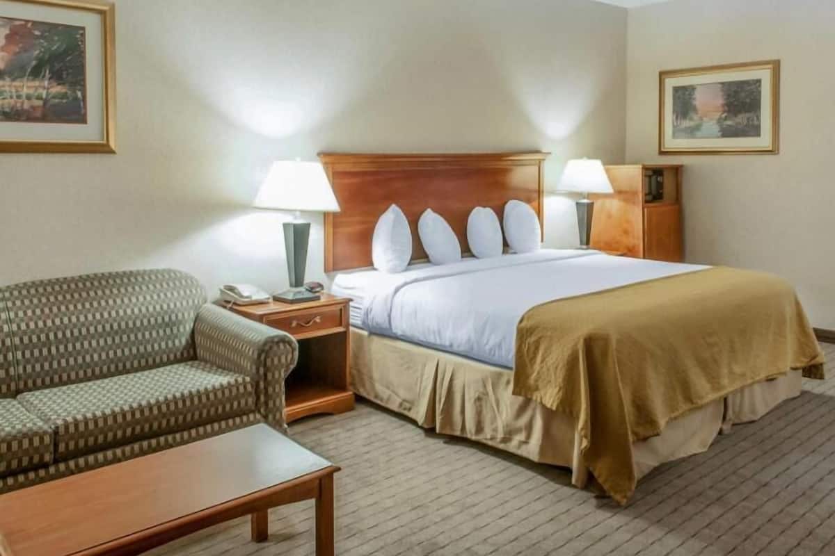 A hotel room with a bed, two bedside lamps, a chair, a nightstand, and a small table.