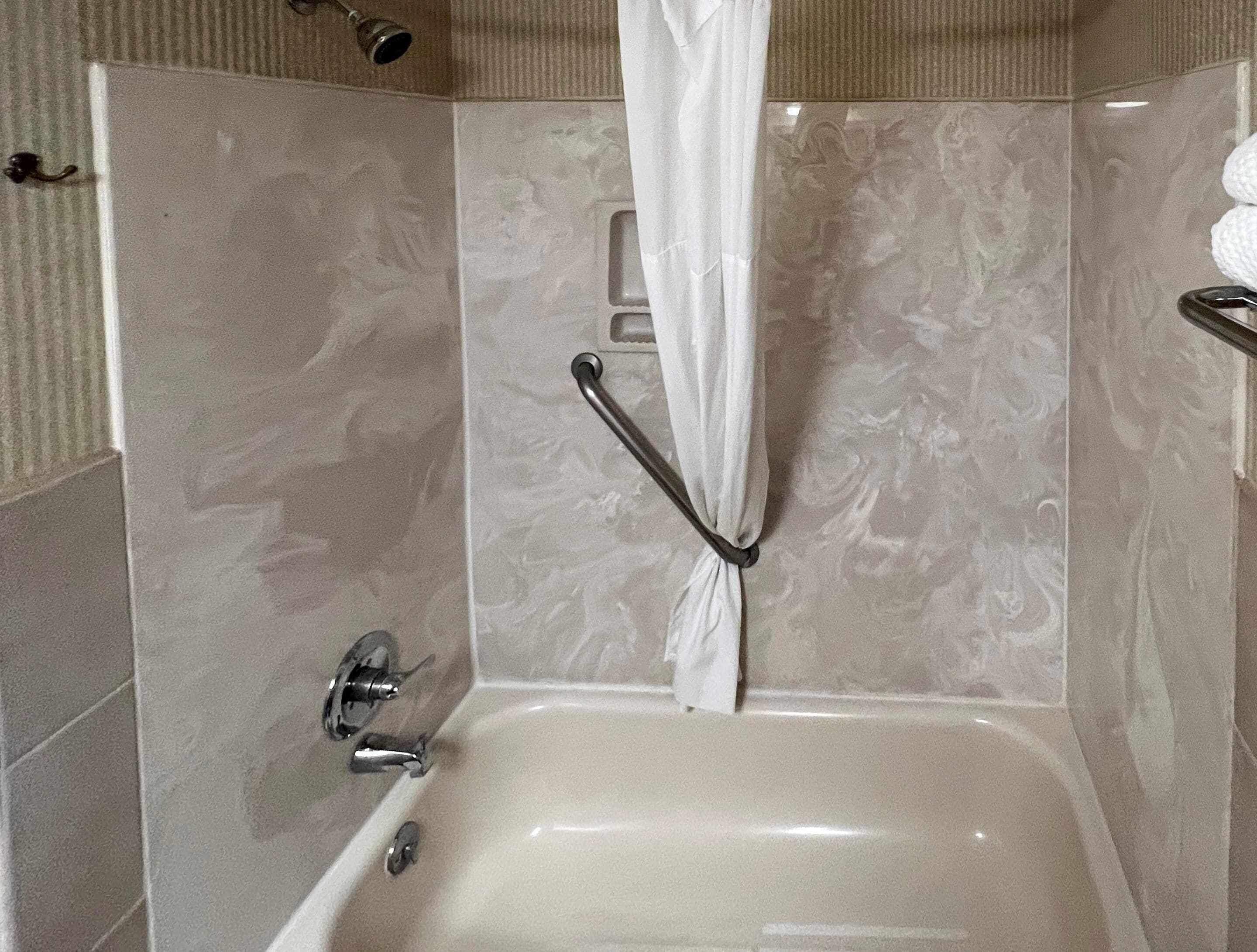Ein Badezimmer mit einer Badewanne, einer Duschvorhang und einem Handtuchhalter.