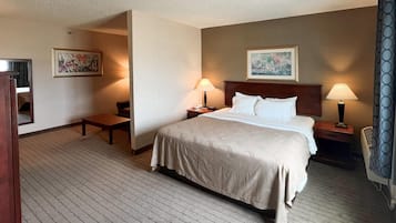 Una habitación de hotel con una cama grande, dos mesitas de noche, un escritorio, una silla y dos lámparas.