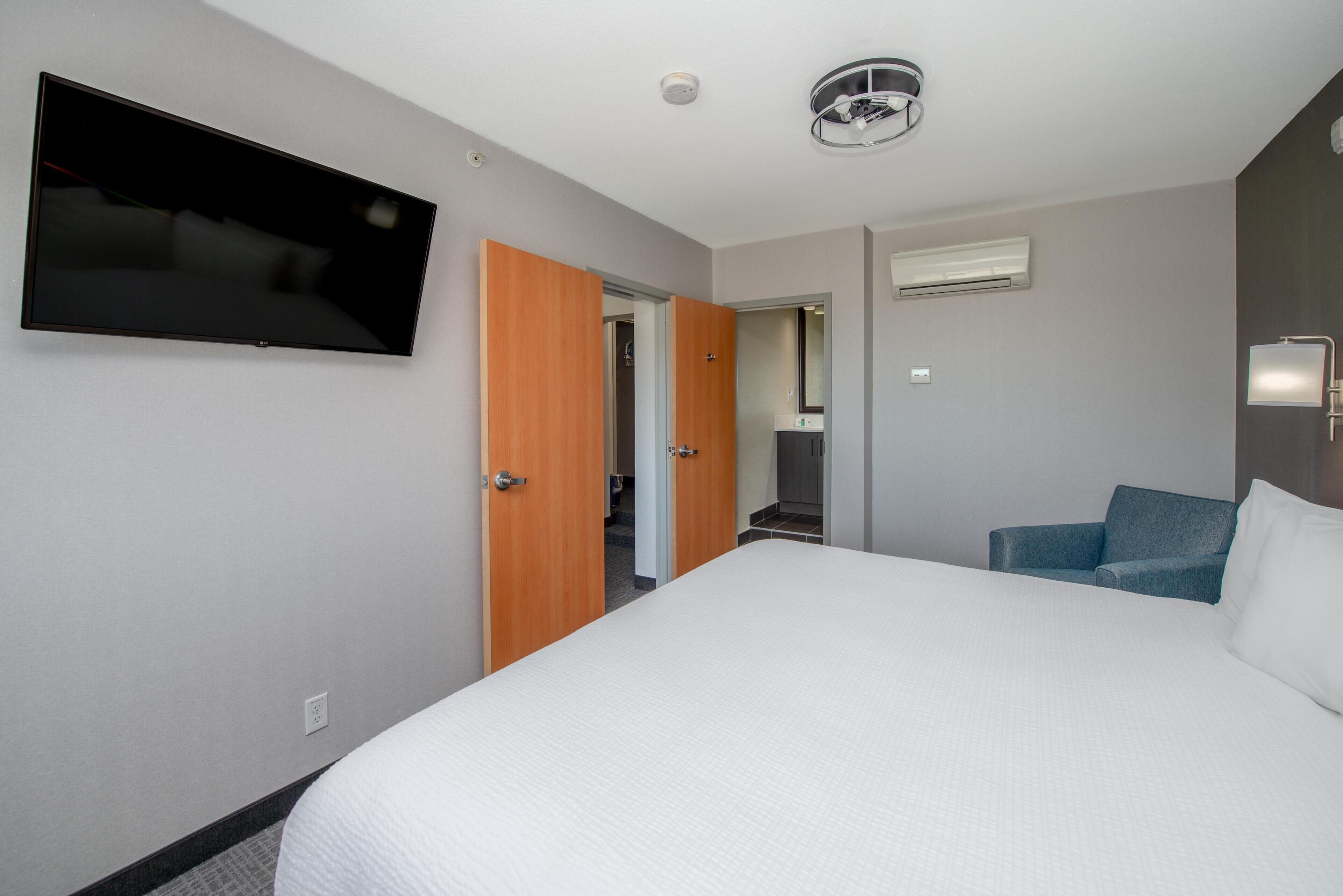 Une chambre d’hôtel équipée d’un lit, d’une télévision, d’une porte et d’un appareil de climatisation.