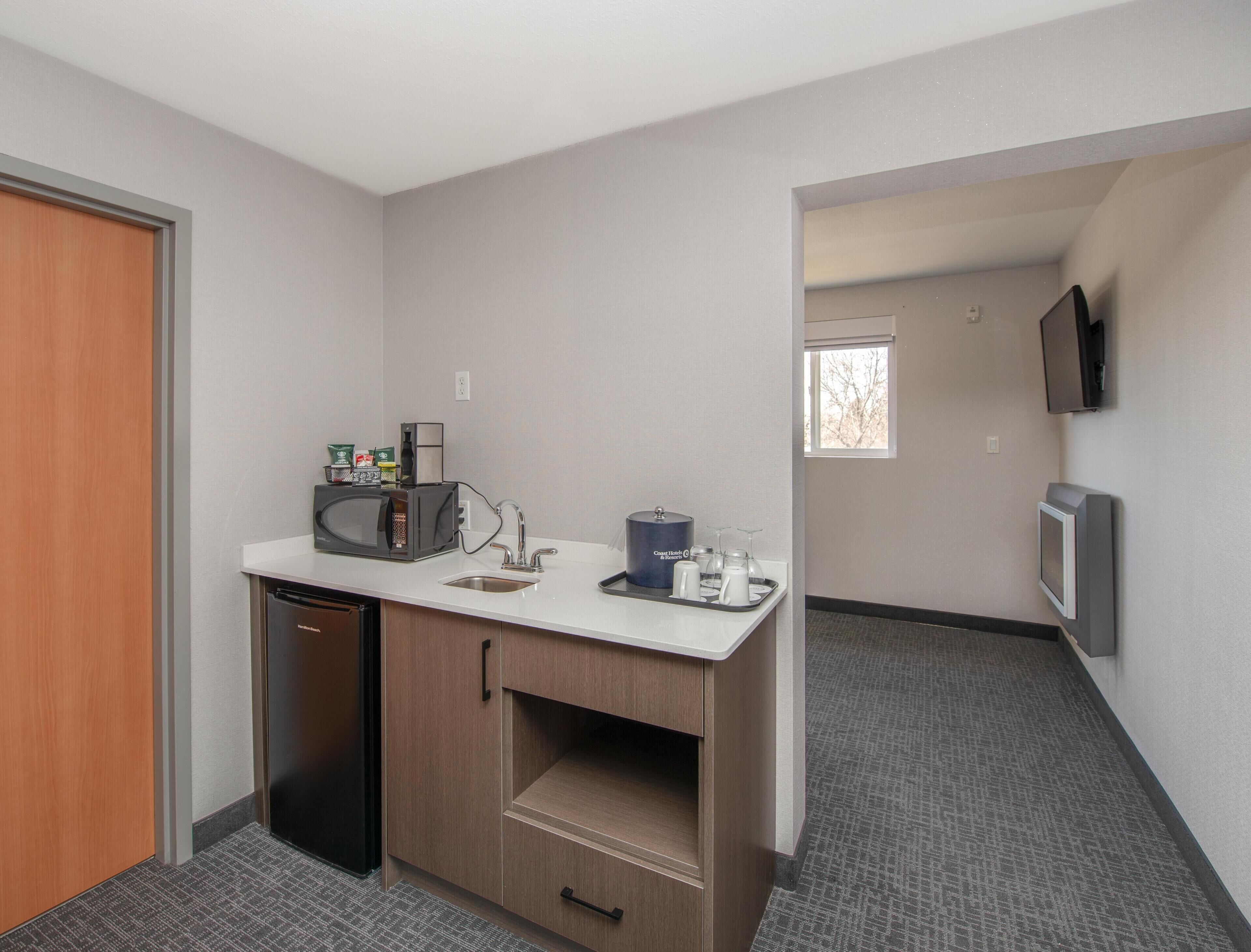 Una kitchenette compacta con microondas, cafetera y lavabo.