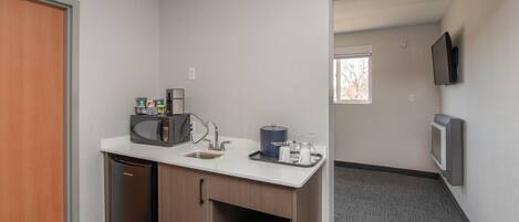 Una kitchenette compacta con microondas, cafetera y lavabo.